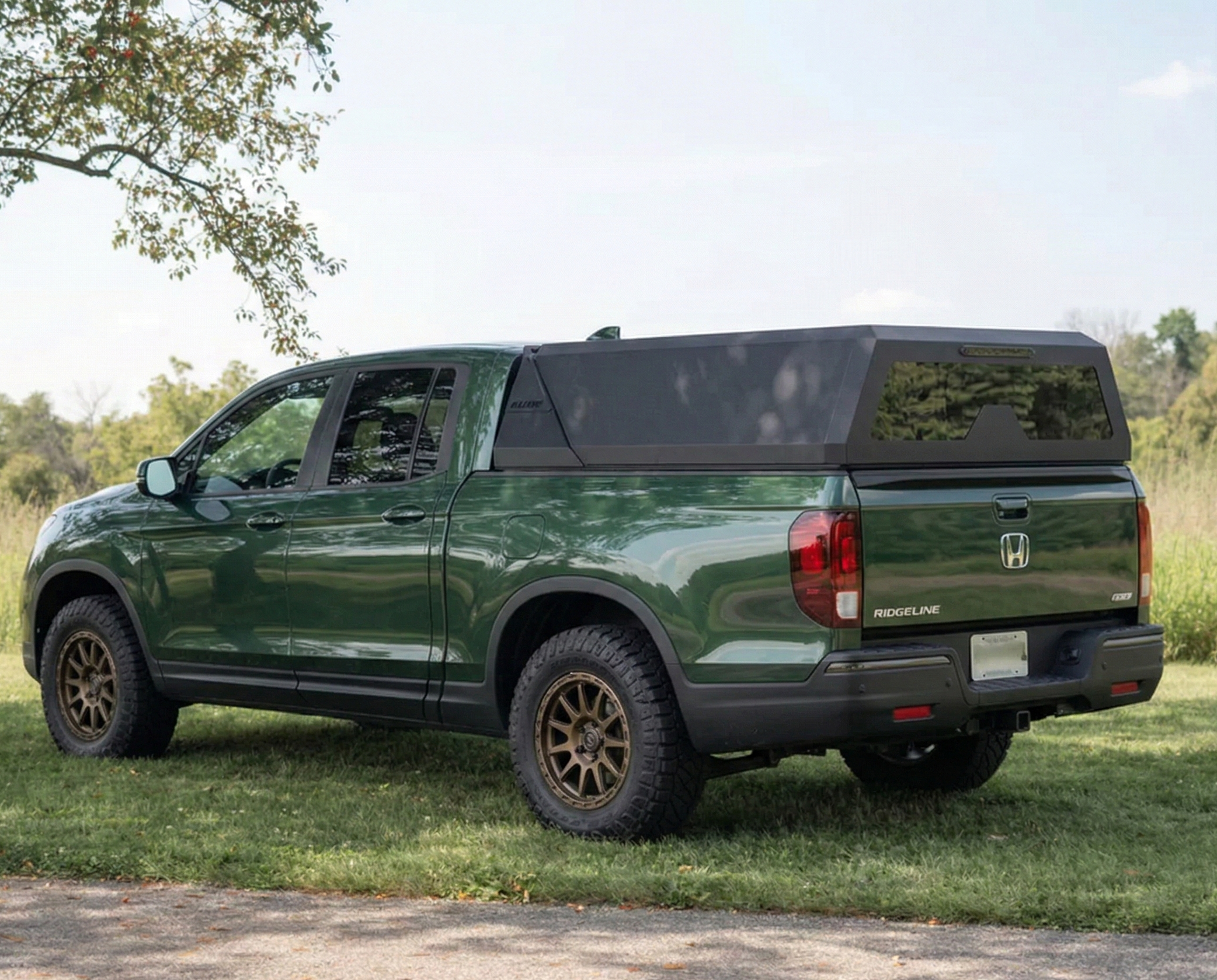 Honda ridgeline truck with open Matrix truck topper parked on grass with trees in the background